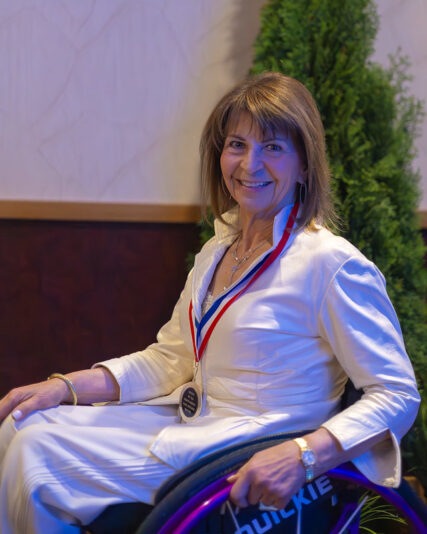 Marilyn Hamilton Smiling while seated wearing her inductee ribbon