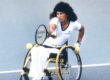 Marilyn Hamilton on the court hitting a tennis ball in match from her wheelchair