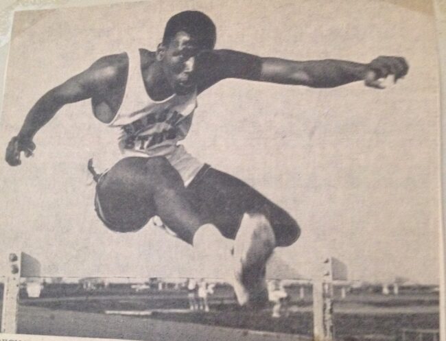 Sid Nikolas long jumping over a hurdle in Track and Field