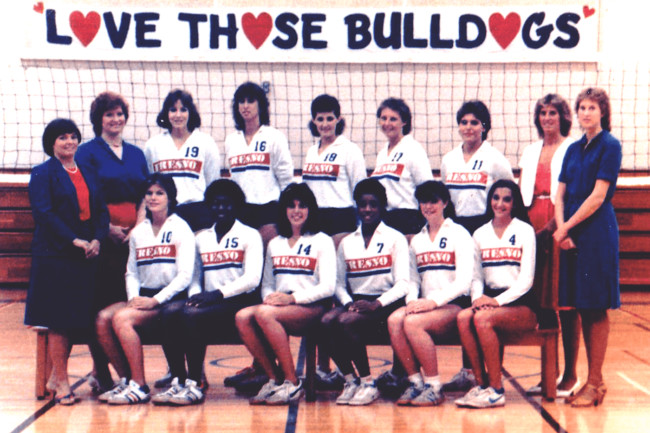 1984 Fresno State Volleyball Team lined up in two rows with their coaches with a banner reading "Love those bulldogs" behind them