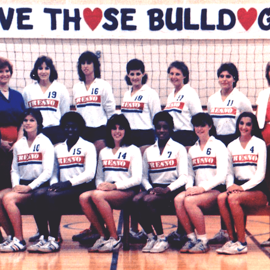1984 Fresno State Volleyball Team lined up in two rows with their coaches with a banner reading "Love those bulldogs" behind them